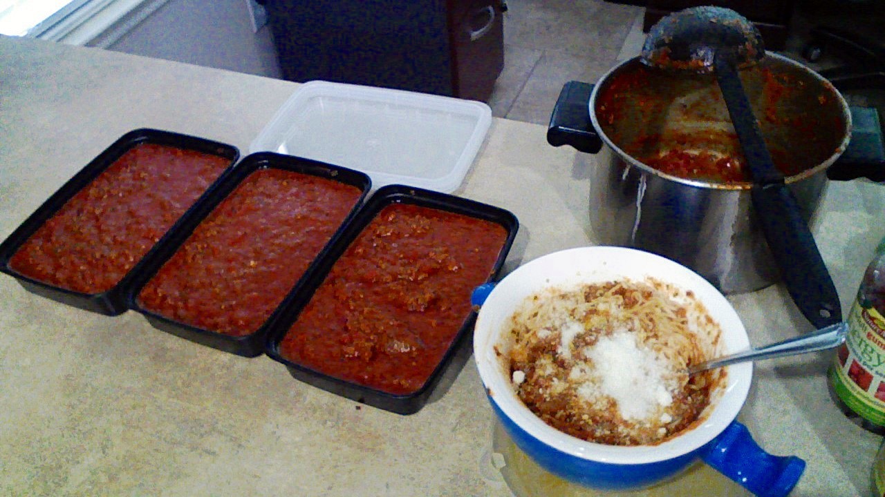 Photograph: Three containers of meat sauce
 next to a bowl of pasta.